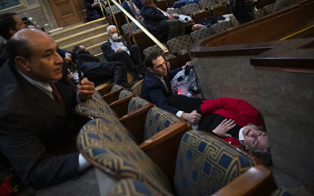 Rep. Jason Crow, D-Colorado, comforts Rep. Susan Wild, D-Pennsylvania, while taking cover as protesters disrupt the joint session of Congress to certify the Electoral College vote on Jan. 6, 2021. (Tom Williams/CQ-Roll Call, Inc via Getty Images)