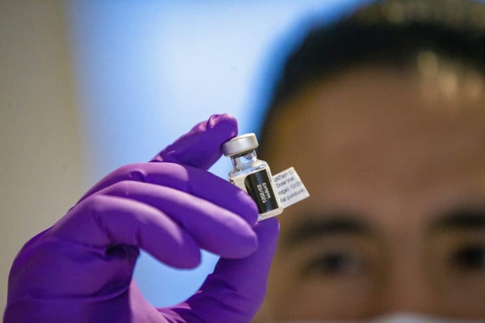Nicholas Capote examines one of the first vials of Pfizer COVID-19 vaccine doses at Tufts Medical Center. (Jesse Costa/WBUR)