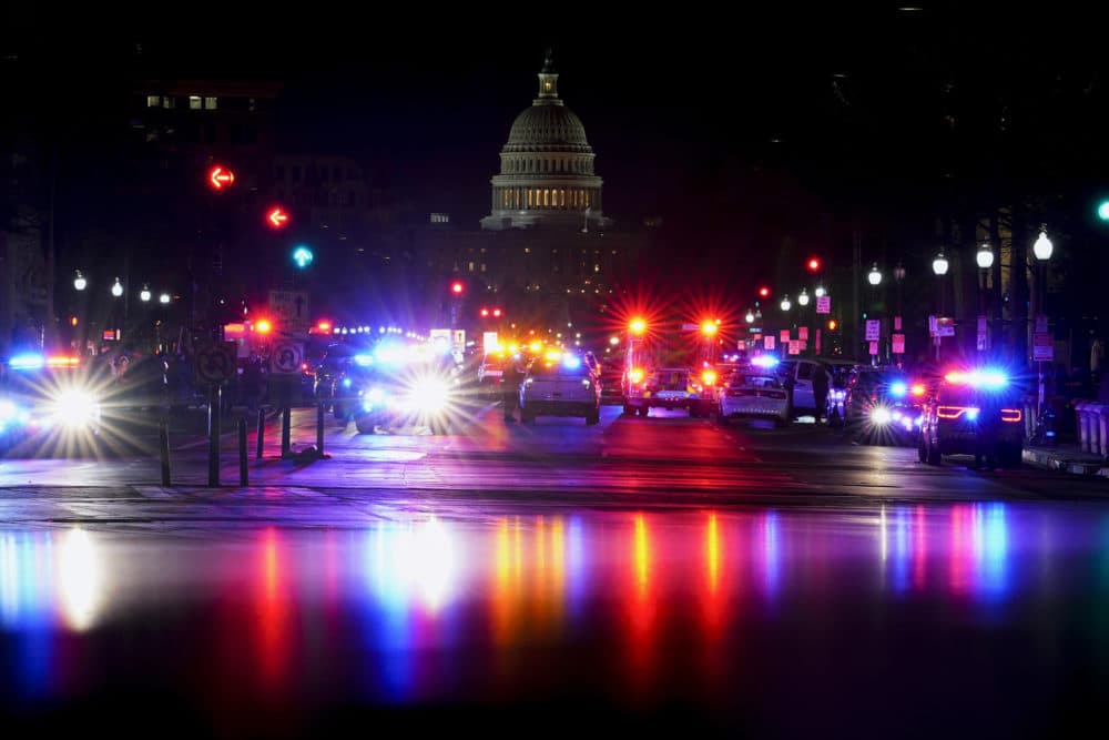 With the U.S. Capitol in the background, lights from police vehicles illuminate Pennsylvania Avenue in Washington, Wednesday, Jan. 6, 2021. (AP Photo/Carolyn Kaster)