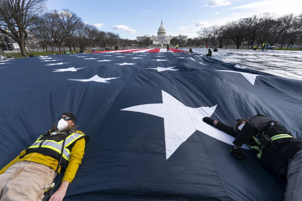 Workers use their body weight to hold down a large American flag placed on the National Mall, with the U.S. Capitol behind them, ahead of the inauguration of President-elect Joe Biden and Vice President-elect Kamala Harris, Monday, Jan. 18, 2021, in Washington. (AP Photo/Alex Brandon)
