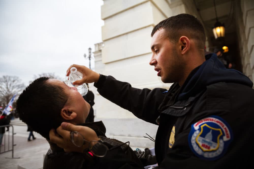 A pro-Trump protester is tended to by a police officer while suffering the effects of chemical agents used to disperse crowds after protesters stormed the grounds the Capitol Building on January 6, 2021 in Washington, D.C. (Jon Cherry/Getty Images)