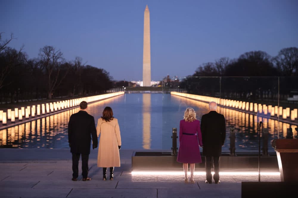 (L-R) Douglas Emhoff, Vice President Kamala Harris, Dr. Jill Biden and President Joe Biden look down the National Mall as lamps are lit to honor the nearly 400,000 American victims of the coronavirus pandemic at the Lincoln Memorial Reflecting Pool January 19, 2021 in Washington, DC. (Chip Somodevilla/Getty Images)