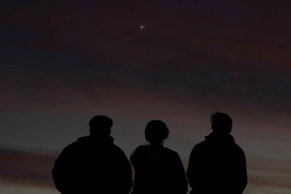 People are silhouetted against the sky at dusk as they watch the alignment of Saturn and Jupiter, Monday, Dec. 21, 2020, in Edgerton, Kansas. (Charlie Riedel/AP)