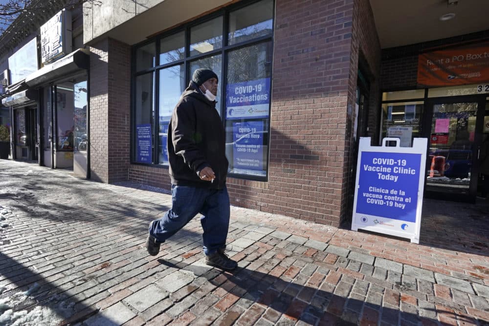 A man walks by the recently opened COVID-19 vaccination site in Chelsea, Feb. 8, 2021. Chelsea's vaccination sites are limited by Massachusetts' eligibility rules. (Elise Amendola/AP)