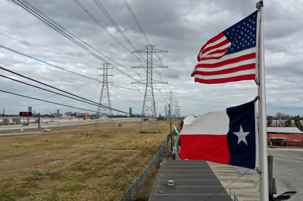 The U.S. and Texas flags fly in front of high voltage transmission towers on Feb. 21, 2021 in Houston, Texas. (Justin Sullivan/Getty Images)