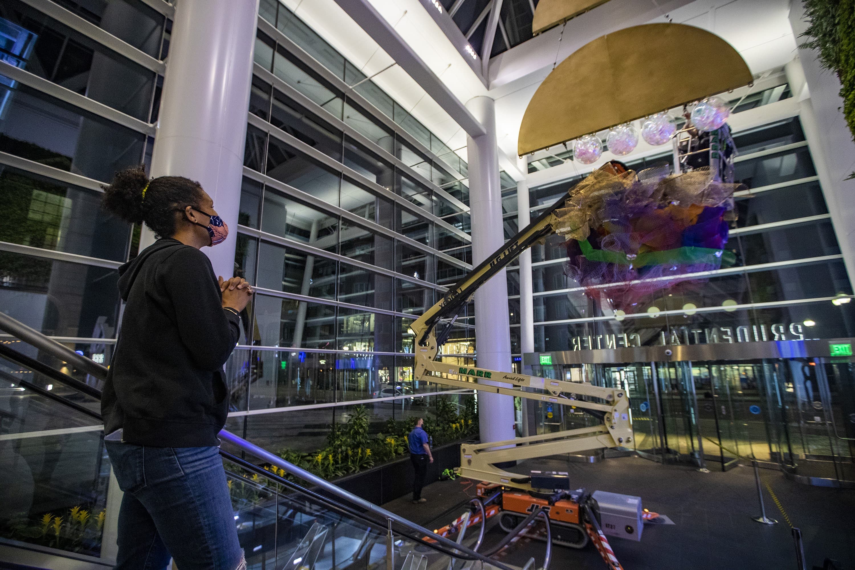 Artist Cicely Carew watches as globes are suspended from her “Alta Major” piece to be installed in the front entrance of the Prudential Center. (Jesse Costa/WBUR)