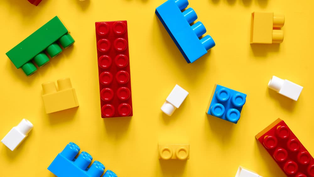 Colorful plastic building blocks flat lay on a yellow background.