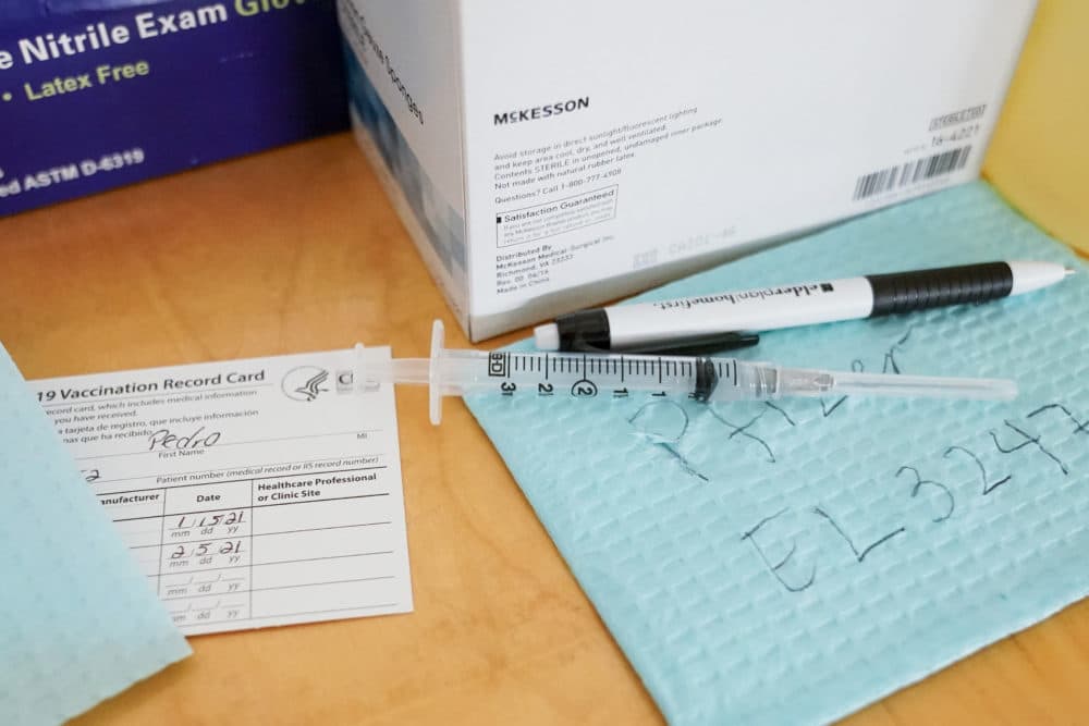A syringe filled with the a COVID-19 vaccine is seen alongside its batch number and a patient's vaccination card at a vaccination site in the East Harlem neighborhood of New York. (Mary Altaffer/AP)