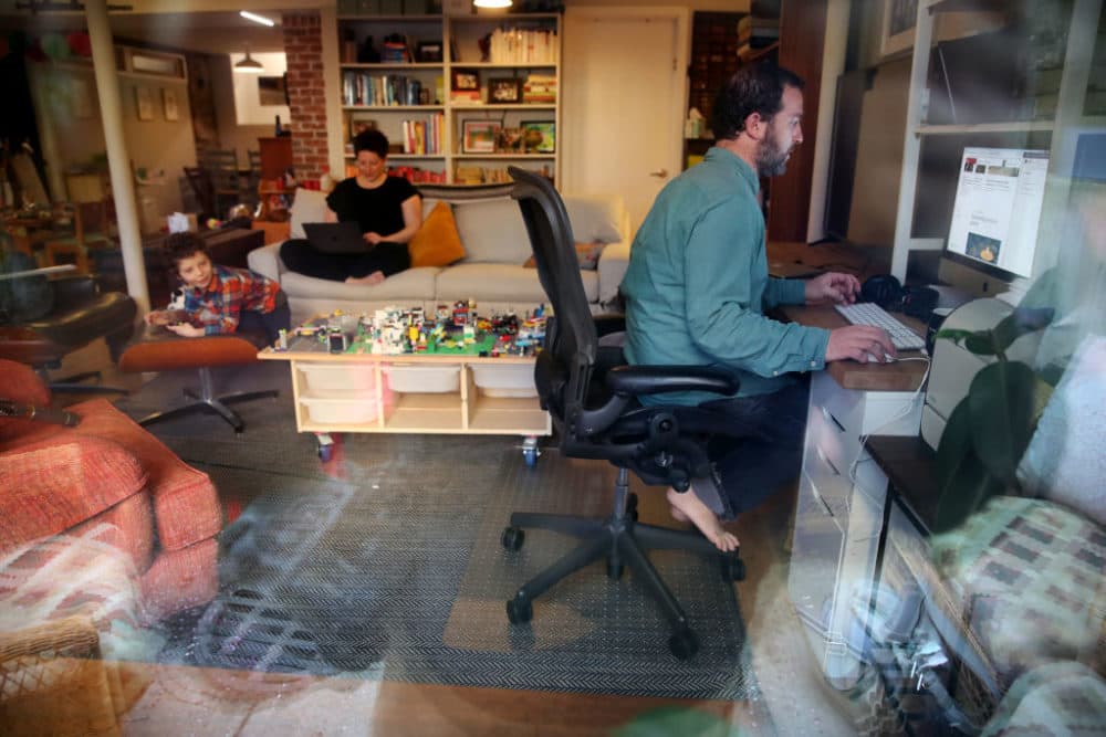 Seth, right, and Nicole Kroll work on their computers while their son Louis, 5, entertains himself at their home in the Jamaica Plain neighborhood of Boston, MA on April 14, 2020. (Craig F. Walker/The Boston Globe via Getty Images)