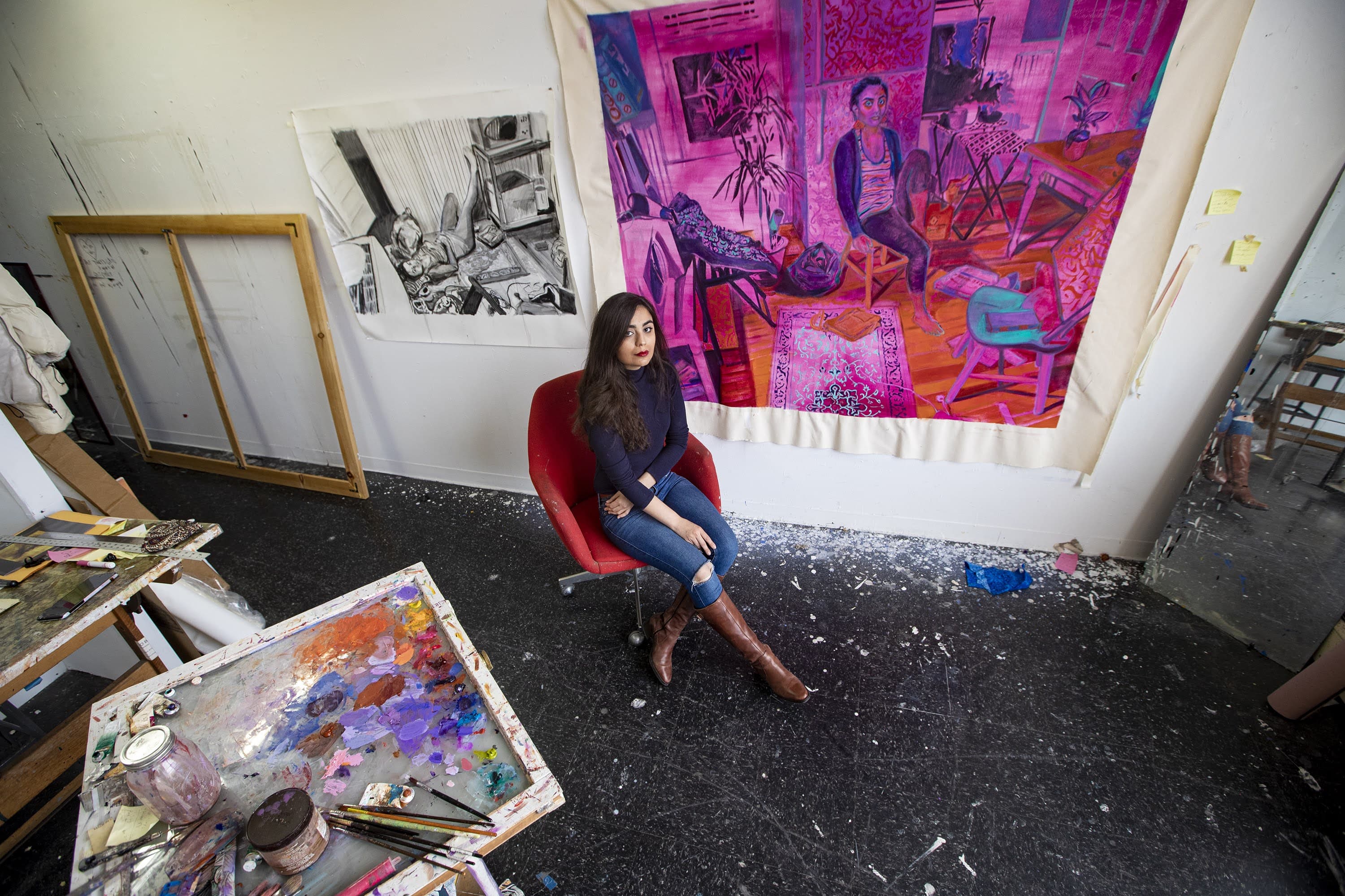 Artist Shabnam Jannesari in front of a painting she is currently working on entitled “62 Sidney Street” at her studio space at the UMass Dartmouth College of Visual and Performing Arts in New Bedford. (Jesse Costa/WBUR)
