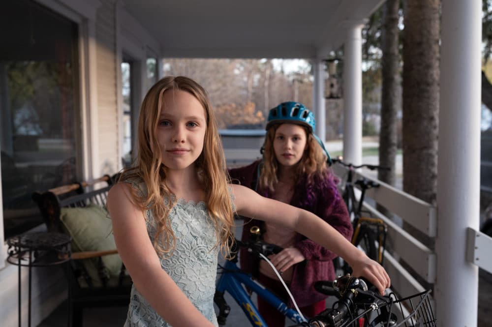 Azalea Morgan, 9, (left) and her sister Ember Morgan, 10, (right) stand with their bikes on the porch of their home in Andover, New Hampshire. The sisters biked to New York City from Andover with their mom to raise awareness of climate change in 2019. (Ryan Caron King/Connecticut Public)