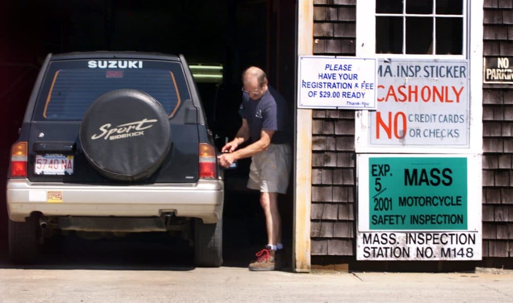Allen Pornovish checks the gas cap during an inspection of a Suzuki Sidekick. (Wendy Maeda/The Boston Globe via Getty Images)