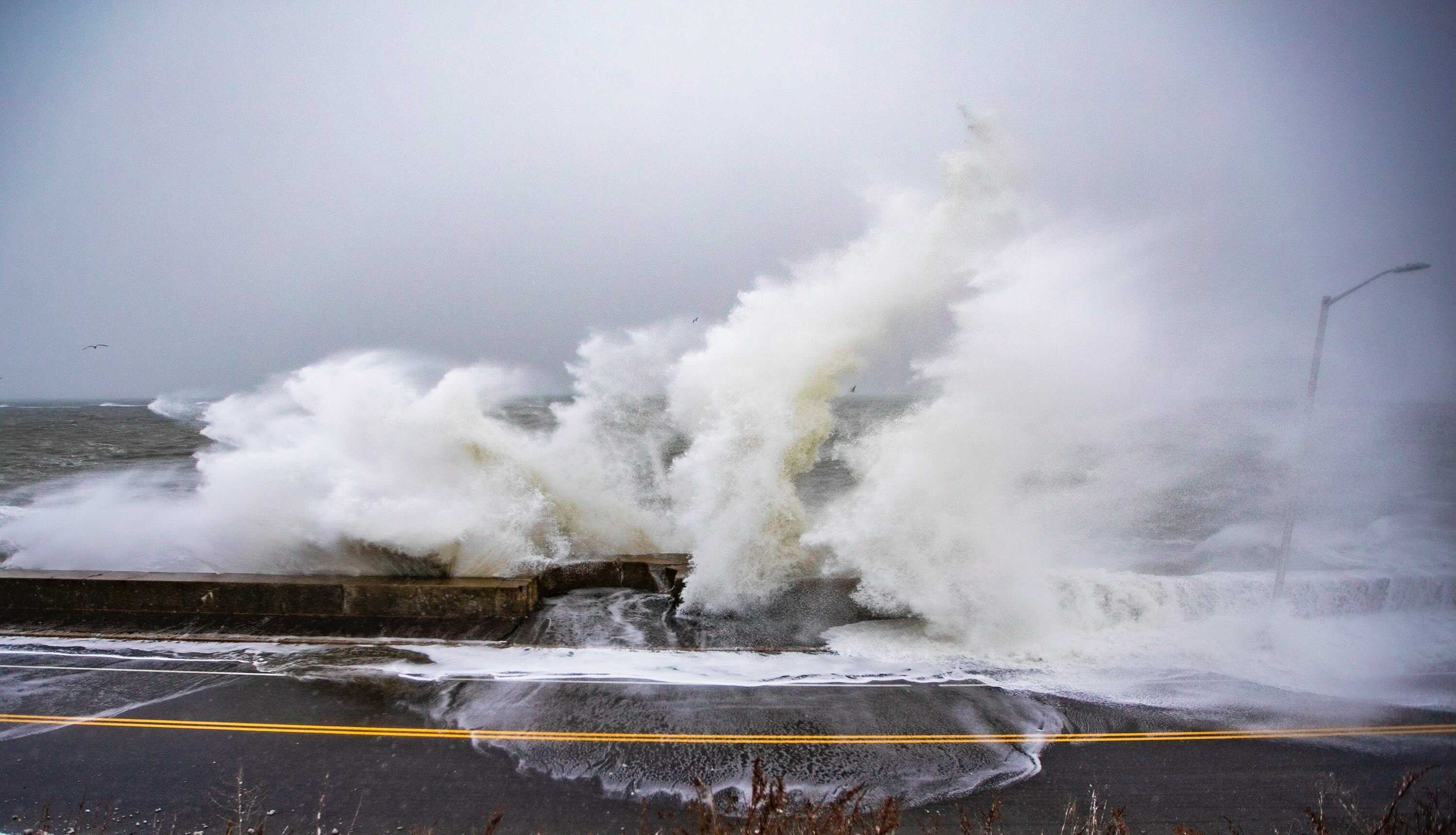 Waves crash over the seawall on Winthrop Parkway in Revere during a high tide on Dec. 17, 2020. (Jesse Costa/WBUR)