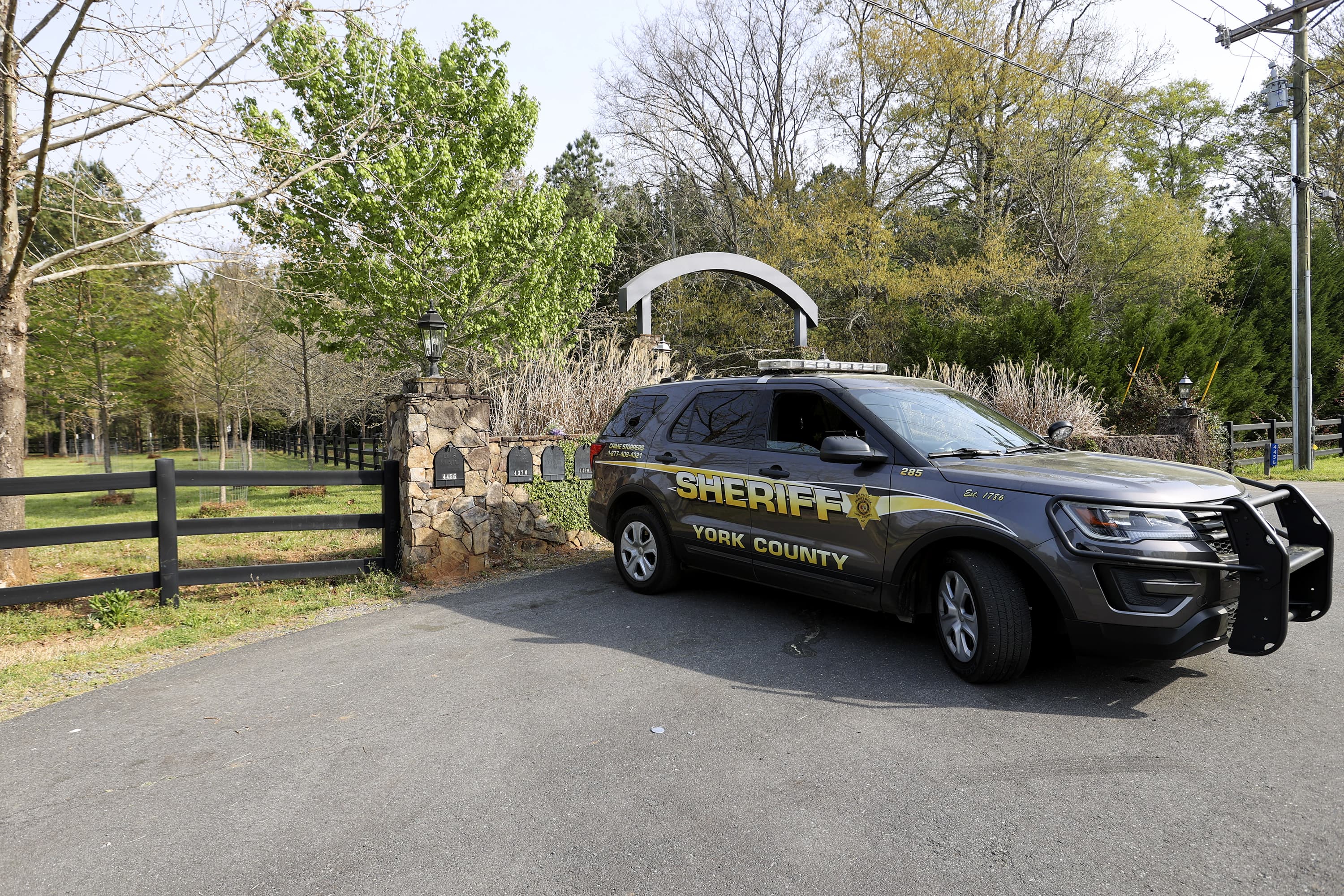A York County sheriff's deputy is parked outside a residence where multiple people, including a prominent doctor, were fatally shot a day earlier, on April 8 in Rock Hill, S.C. (Nell Redmond/AP)