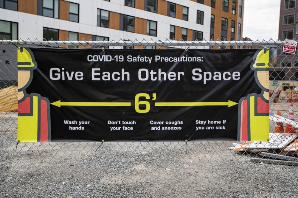 A COVID-19 safety precaution sign at a construction site in Central Square in Cambridge. (Jesse Costa/WBUR)