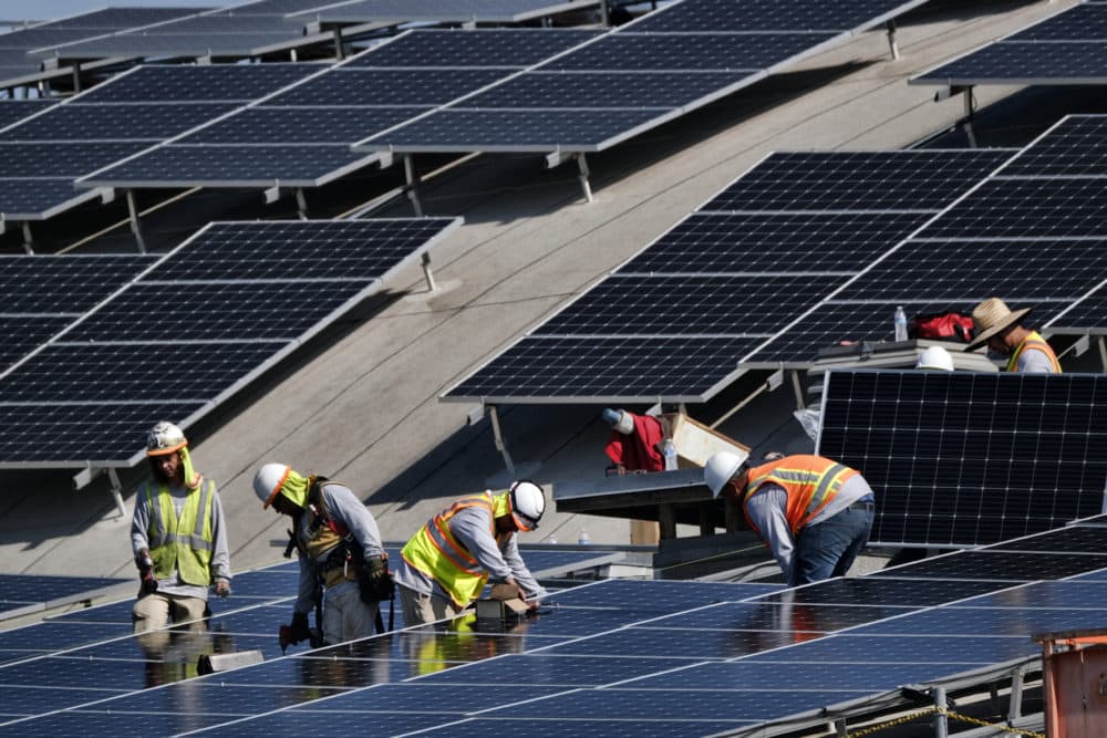 Workers install solar panels onto a roof in Los Angeles. (Richard Vogel/AP)