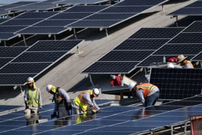 Workers install solar panels onto a roof in Los Angeles. (Richard Vogel/AP)