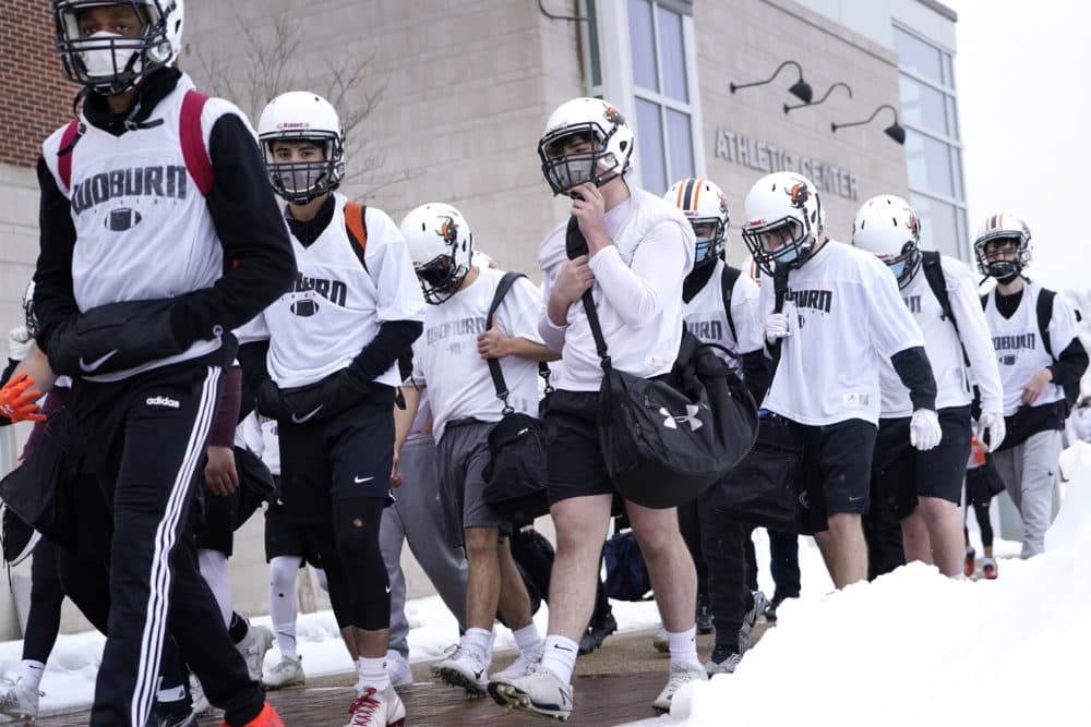 Varsity football players wear face masks as they walk to the field for the first day of practice at Woburn High School on Feb. 22, 2021. (Elise Amendola/AP)