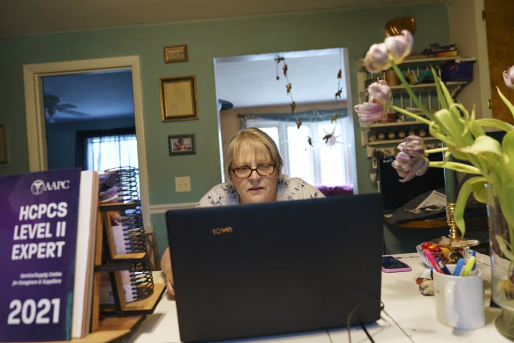 Ellen Booth, 57, studies at her kitchen table to become a certified medical coder, in Coventry, R.I., May 17, 2021. When the restaurant she worked for closed last year, Booth said it gave her &quot;the kick I needed.&quot; She started a year-long class to learn to be a medical coder. (David Goldman/AP)