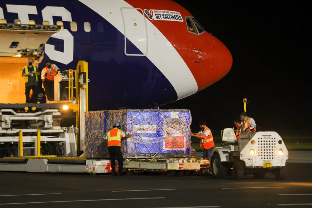 In this photo provided by El Salvador's presidential press office, airport workers unload a container of Chinese-made Sinovac COVID-19 vaccines from The New England Patriots team plane at the airport in San Salvador, El Salvador, Wednesday, May 19, 2021. (El Salvador's presidential press office via AP)