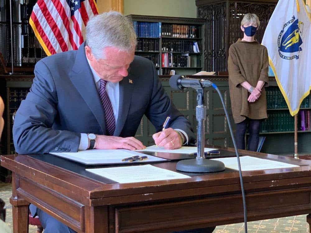 Gov. Charlie Baker signs an order ending the state of emergency put in place during the COVID-19 pandemic. (Steve Brown/WBUR)