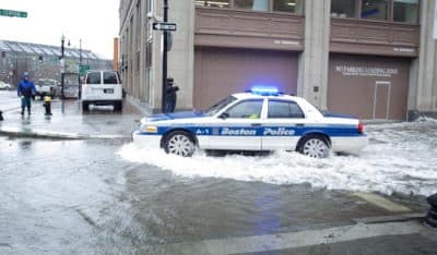 A police car navigates through floodwaters on Central St. to reach Atlantic Ave. (Robin Lubbock/WBUR)