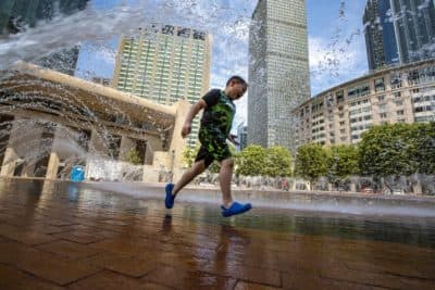 Seven-year-old Matthew (no last name given) runs beneath the arches of cascading water at the fountain on the Christian Science Plaza in Boston. (Jesse Costa/WBUR)