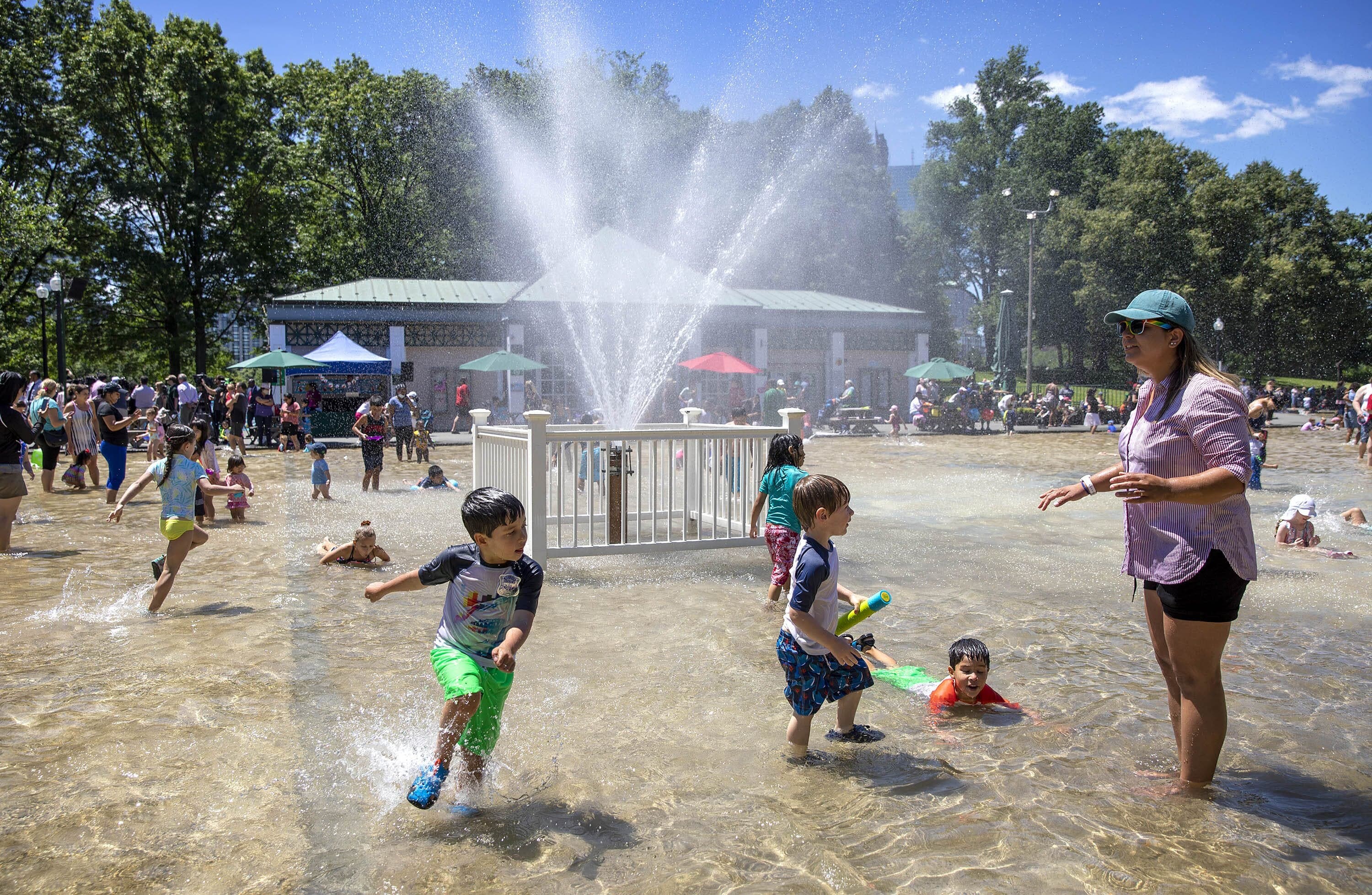Children splash through the water by the fountain at the summer opening of Boston's Frog Pond.