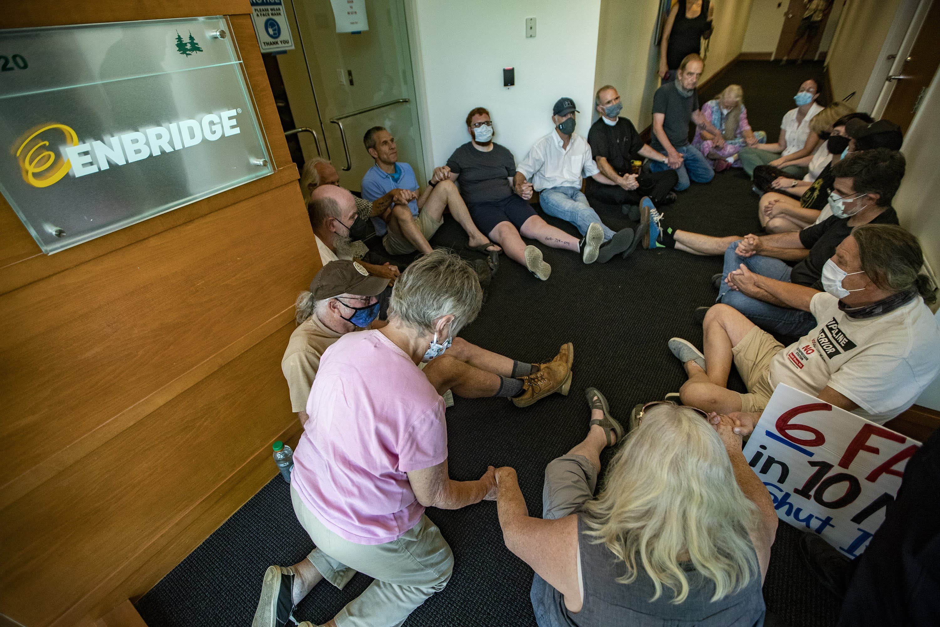 A group of protesters gather near the front door of the Enbridge office in Waltham. (Jesse Costa/WBUR)