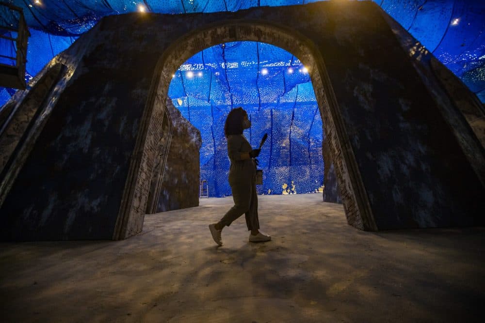 Firelei Báez walks with a brush and paint can in hand as she works on her largest sculptural installation to date, a reimagined version of the archeological ruins of the Sans-Souci Palace in Haiti installed at the ICA Watershed in East Boston. (Jesse Costa/WBUR)