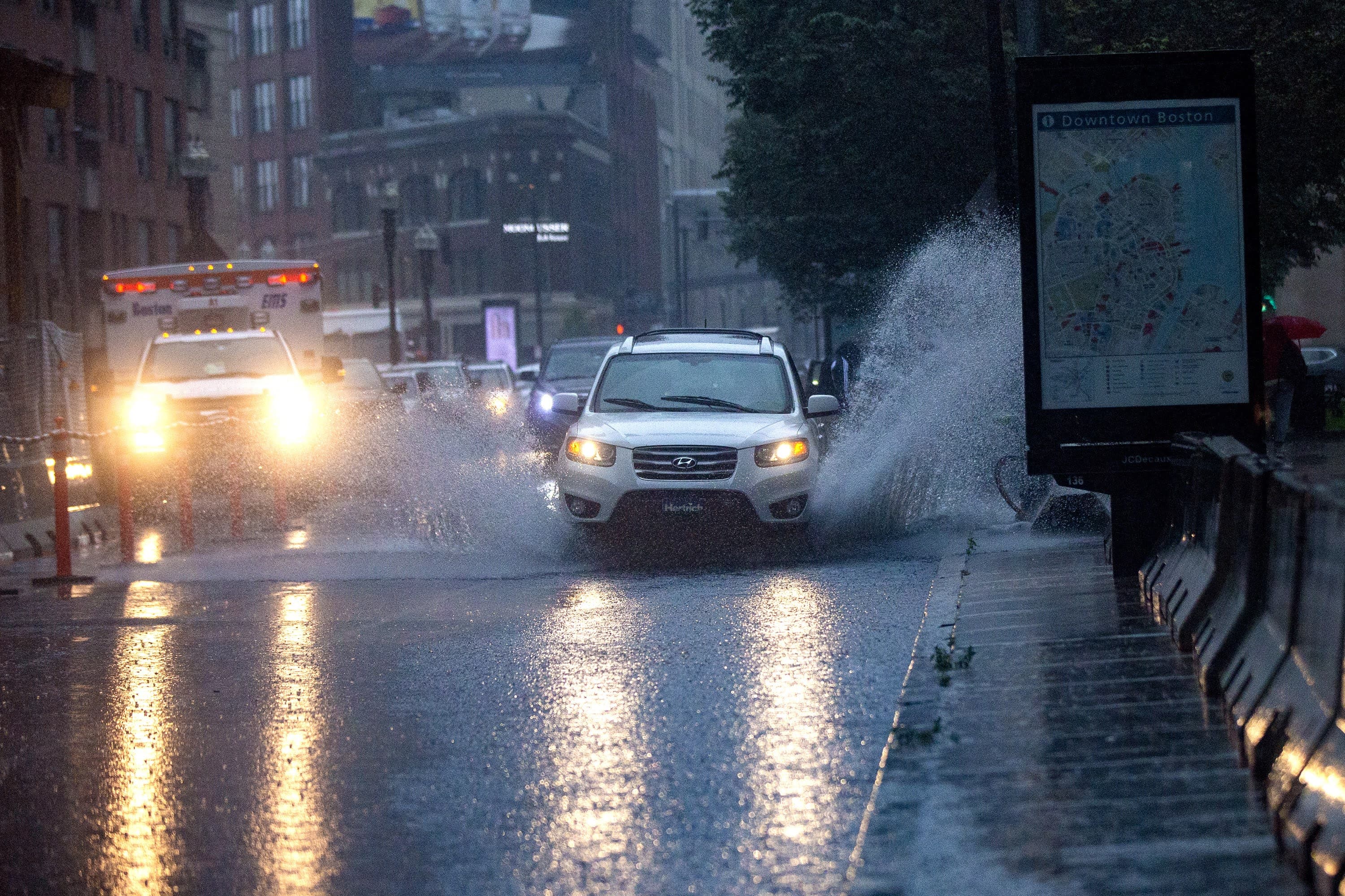 Cars drive through a flooded Stuart Street during the heavy rain from Tropical Storm Elsa. (Jesse Costa/WBUR)