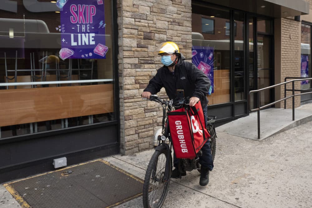 A delivery man bikes with a food bag from Grubhub. (Mark Lennihan/AP)