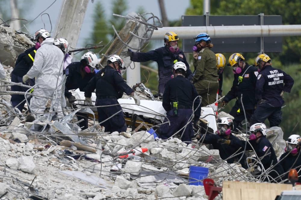 Monday, July 5, 2021: Rescue workers move a stretcher containing recovered remains at the site of the collapsed Champlain Towers South condo building, in Surfside, Fla. (Lynne Sladky/AP)