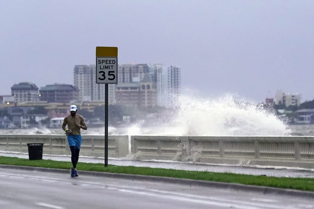 A jogger makes his way in Tampa, Fla. as a wave breaks over a seawall, during the aftermath of Tropical Storm Elsa Wednesday, July 7, 2021. The Tampa Bay area was spared major damage as Elsa stayed off shore as it passed by. (John Raoux/AP)