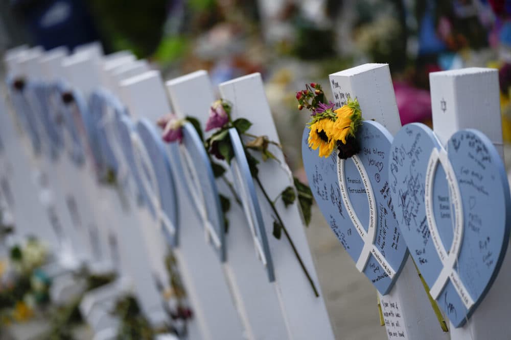 Flowers and messages of love adorn wooden hearts with the names of victims of the Champlain Towers South building collapse, at a makeshift memorial near the site, on Monday, July 12, 2021, in Surfside, Fla.(AP Photo/Rebecca Blackwell)