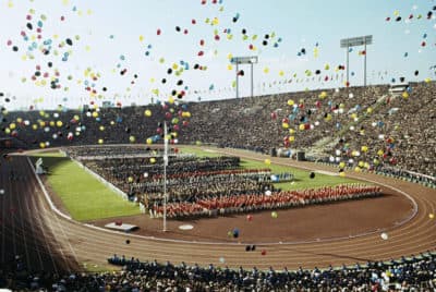 On this Oct. 10, 1964, file photo, balloons fly over Olympians and spectators during the opening ceremony of the 1964 Summer Olympics at the National Stadium in Tokyo. The famous 1964 Tokyo Olympics highlighted Japan’s resiliency. It was a prospering country that was showing off bullet trains, transistor radios, and a restored reputation just 19 years after devastating defeat in World War II. (AP)