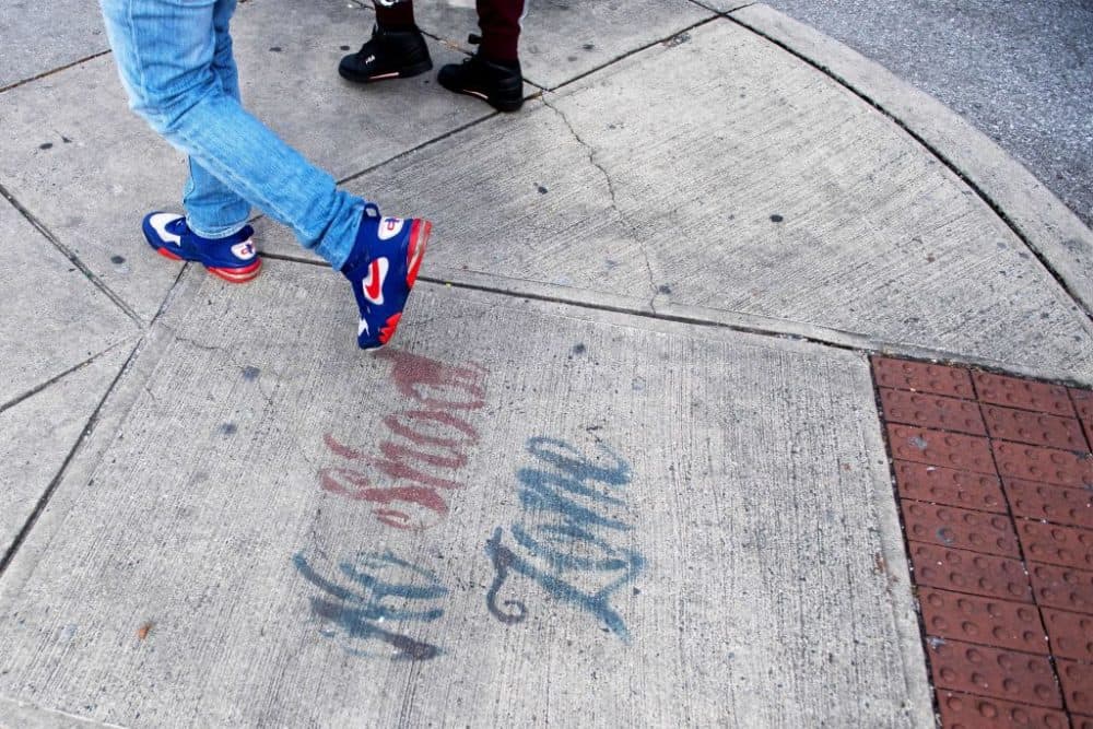 Two men walk past a sign spray painted on the sidewalk stating &quot;No Shoot Zone&quot; in Baltimore, Maryland, on Dec. 17, 2018. (Jim Watson/AFP/Getty Images)