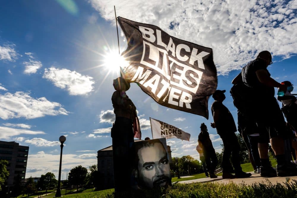 A woman holds a Black Lives Matter flag during an event in remembrance of George Floyd outside the Minnesota State Capitol on May 24, 2021. (Kerem Yucel/AFP via Getty Images)