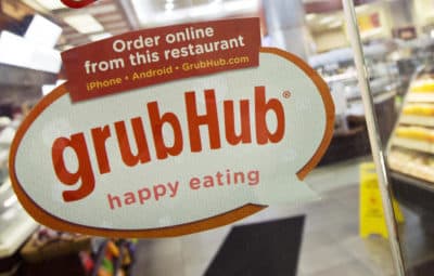 In this 2014 file photo, a sign with the old GrubHub logo is displayed is displayed on the door to a New York restaurant. (Mark Lennihan/AP)