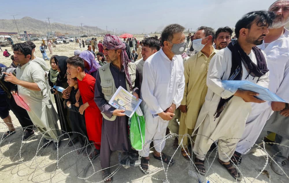 A man holds a certificate acknowledging his work for Americans as hundreds of people gather outside the international airport in Kabul, Afghanistan, Aug. 17, 2021. Deadly chaos gripped the main airport as desperate crowds tried to flee the country. (AP Photo)