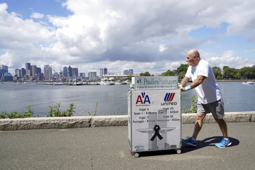 Paul Veneto pushes a beverage cart along the Boston harbor on Saturday. Veneto, a former flight attendant who lost several colleagues when United Flight 175 was flown into the World Trade Center on Sept. 11, 2001, is honoring his friends on the 20th anniversary of the terrorist attacks by pushing the beverage cart from Boston to ground zero in New York. (Mary Schwalm/AP)