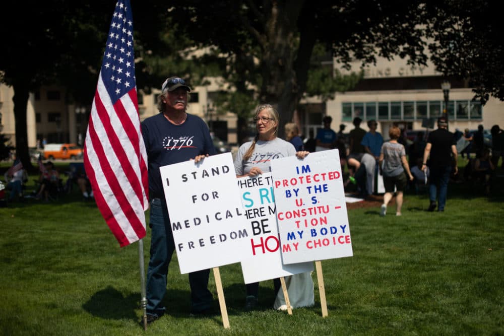 A couple holds sign as they join hundreds of other demonstrators gathering to protest against mandated vaccines outside of the Michigan State Capitol on August 6, 2021 in Lansing. There were 44 counties in Michigan at high or substantial levels of community coronavirus transmission, according to the CDC as of August 5, 2021. (Emily Elconin/Getty Images)