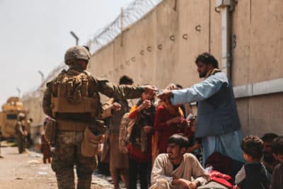 A marine with the 24th Marine Expeditionary unit (MEU) passes out water to evacuees during the evacuation at Hamid Karzai International Air. (Isaiah Campbell/U.S. Marine Corps via Getty Images)