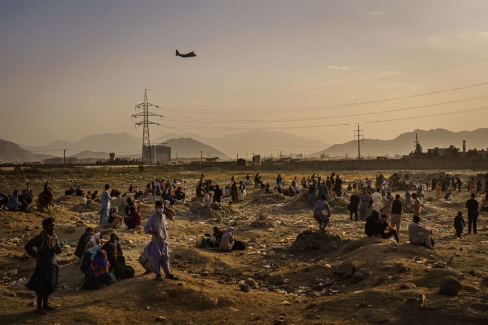 A military transport plane launches off while Afghans who cannot get into the airport to evacuate, watch and wonder while stranded outside, in Kabul, Afghanistan. (Marcus Yam / Los Angeles Times via Getty Images)