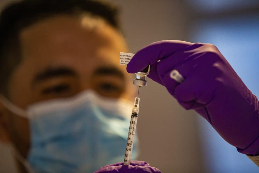 Nicholas Capote looks at the first Pfizer COVID-19 vaccine dose at Tufts Medical Center in Boston in December 2020. (Jesse Costa/WBUR)