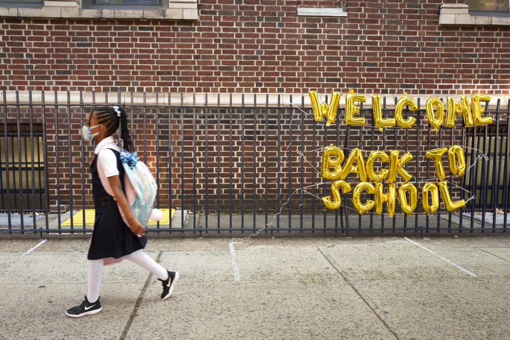 A girl passes a &quot;Welcome Back to School&quot; sign as she arrives for the first day of class an elementary school in New York on Sept. 13, 2021. (Mark Lennihan/AP/File)