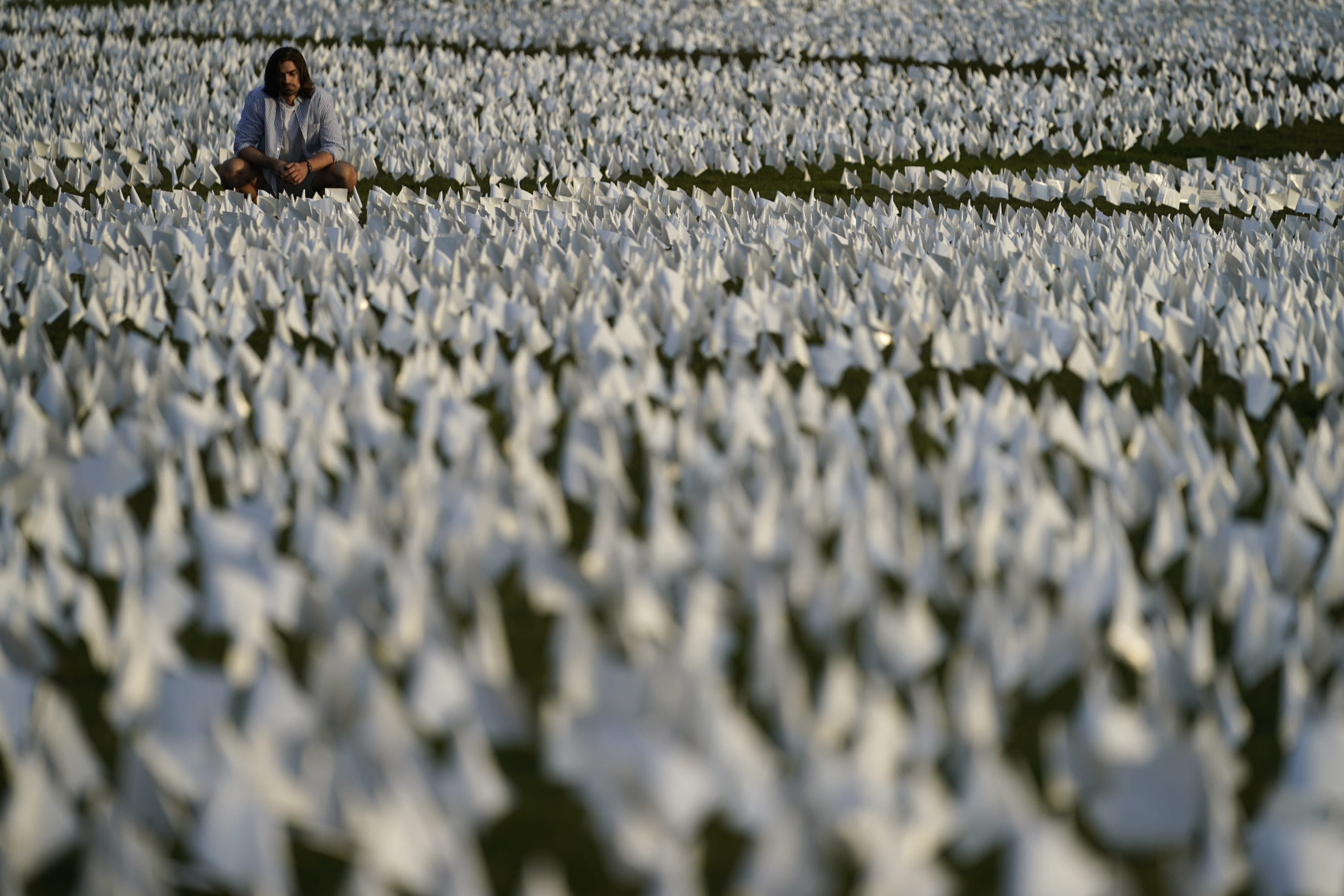A person looks at white flags that are part of artist Suzanne Brennan Firstenberg's temporary art installation, &quot;In America: Remember,&quot; in remembrance of Americans who have died of COVID-19, on the National Mall in Washington on Sept. 17, 2021. (Brynn Anderson/AP)