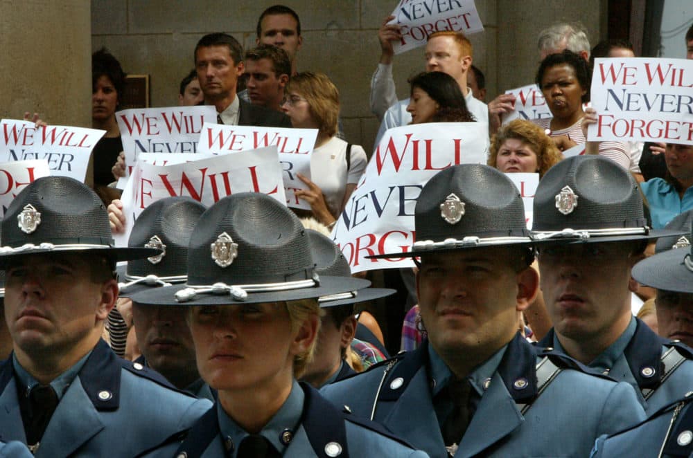 Passersby hold up signs as an Honor Guard of State Troopers stands at attention outside Faneuil Hall, where a Massachusetts Remembrance Ceremony was held in 2002 to mark the one-year anniversary. (Barry Chin/The Boston Globe via Getty Images)