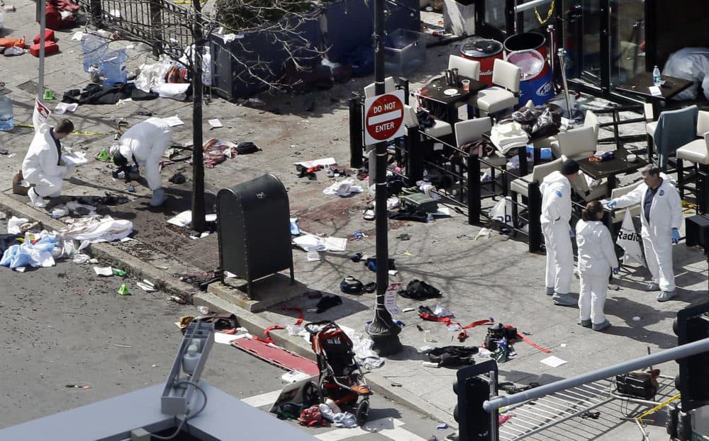 In this April 16, 2013 photo, investigators examine the scene of the second bombing outside the Forum Restaurant on Boylston Street near the finish line of the 2013 Boston Marathon, a day after two blasts killed three and injured more than 260 people. (Elise Amendola/AP)