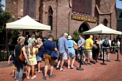 People line up and put on masks as they prepare to enter the Salem Witch Museum in Salem on Aug. 11, 2021. Salem has mandated that masks be worn indoors throughout the city. (John Tlumacki/The Boston Globe via Getty Images)